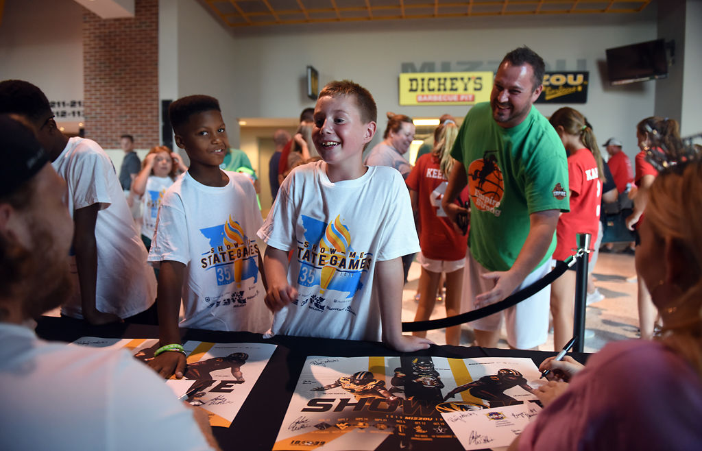 Dax Gauert, 9, under the instruction of his father, Curt Gauert, asks Mizzou football's Dawson Downing what his favorite NFL team is